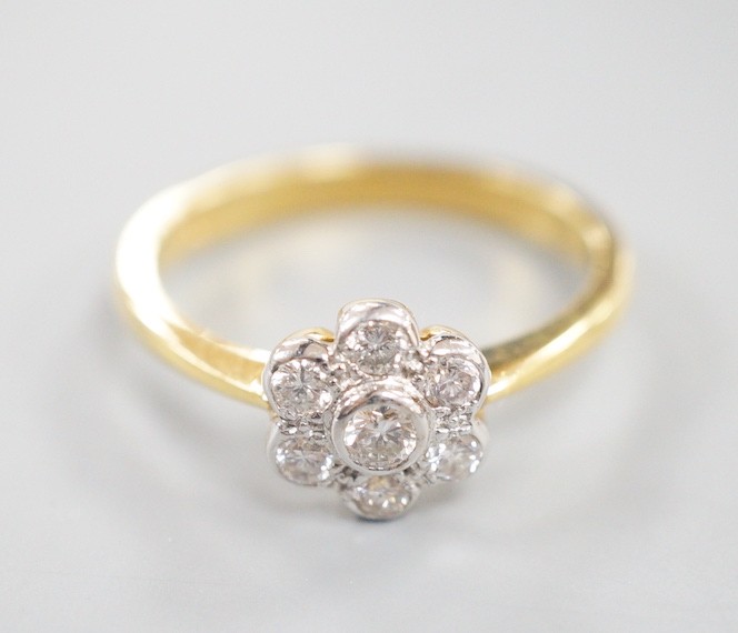 A modern 18ct gold and collet set seven stone diamond set flower head cluster ring, size O, gross weight 3.7 grams